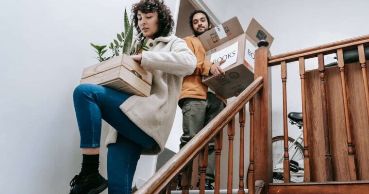 Couple going down the stairs while carrying boxes